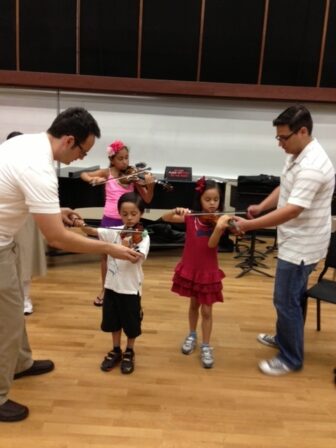 SDSU Community Music School teachers work with young string students.