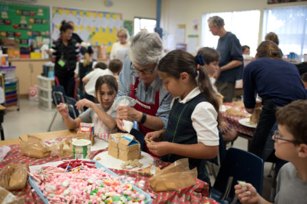Ms. Fink helps third grade students build gingerbread houses. Photo courtesy of Rosanna Barr Photography. 