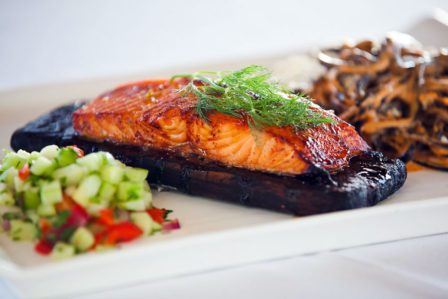 Salmon is prepared and served on a plank for extra flavor. 